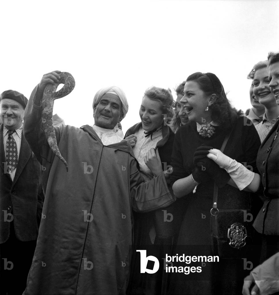 A local man shows off a snake to a group of fascinated French actresses during their visit to Marrakech, Morocco
December 1952 C5919-012