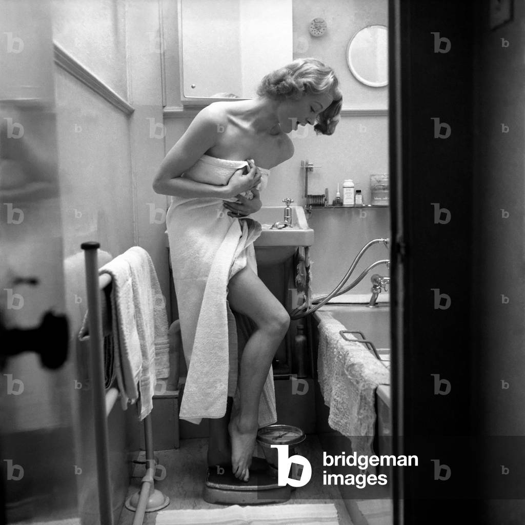 Women: Weight. Actress Pat Dainton weighing herself. October 1953