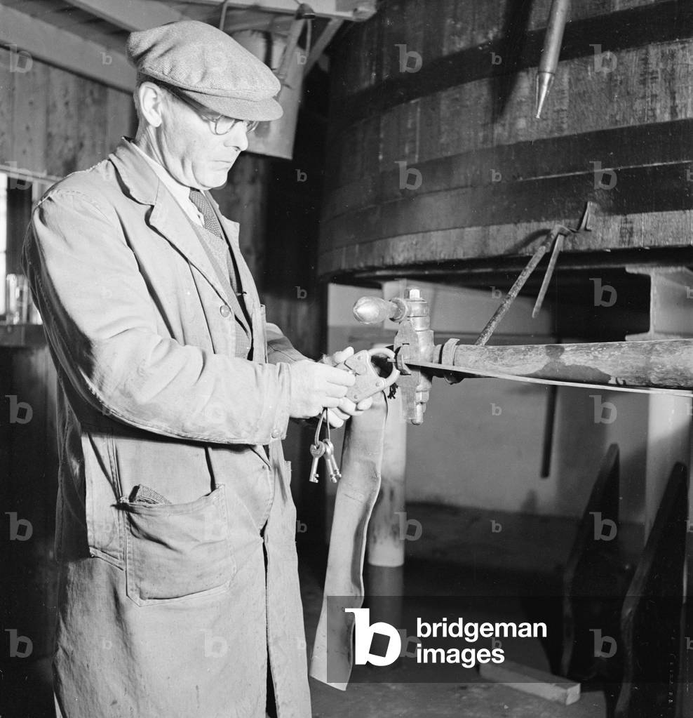 Foreman at the AGlenlivet Distillery seen here unlocking the alcohol safe so sherry casks can be filled with their finest single malt whisky . The barrels will then be sent to the bonded warehouse where it willl mature for a minimum of eight years. Circa 1948
