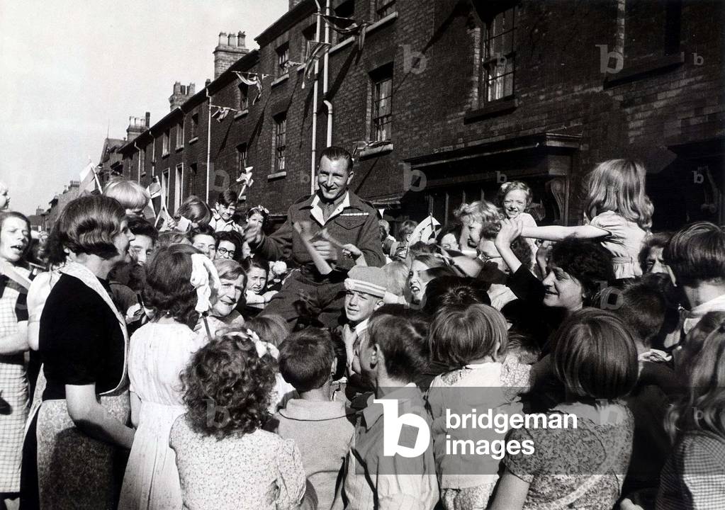 30 Year Old Pte Jim Kavanagh of Edward Street Birmingham could not get home for VJ Day, so the children waited until he did return before having their peace day celebration, 1945 (b/w photo)