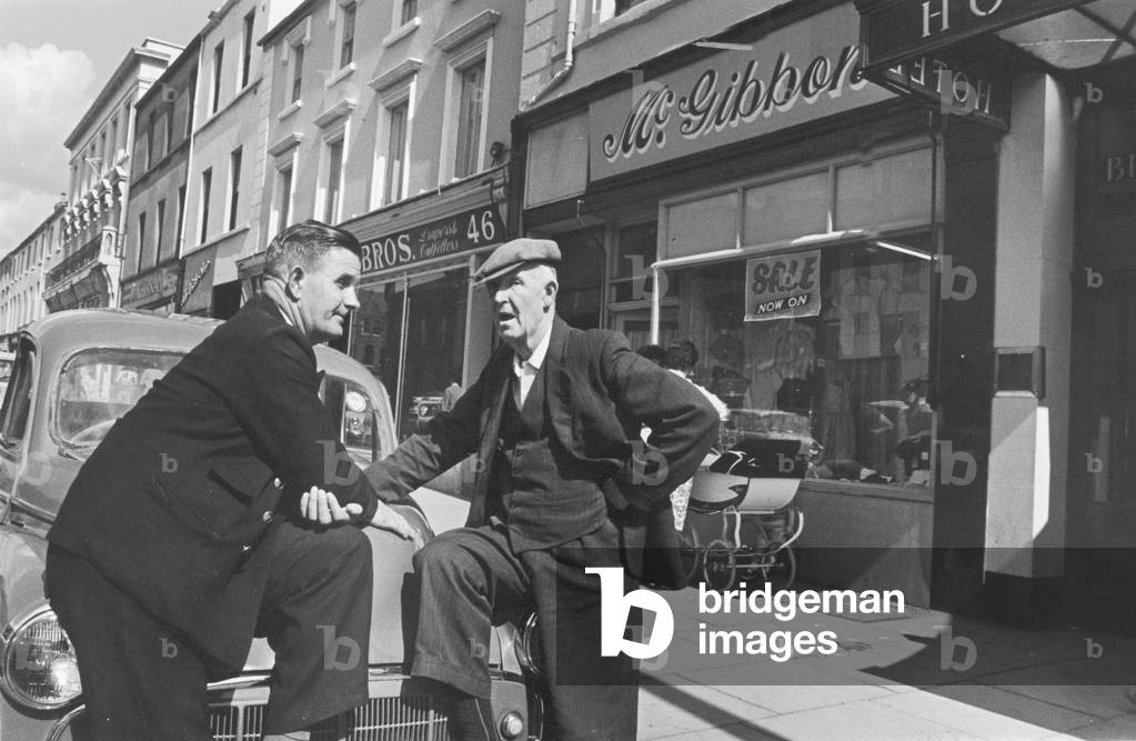 To gentlemen seen here outside the main parade of shops in Lurgan, catching up with all the local news. Circa 1966