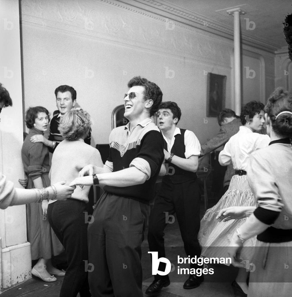 The London Jive Club in Baker Street is probably the only club which has a dancing school held on weekday evenings to teach not only ballroom dancing, but Jive, Jitterbug, skiffle and any other new dance that comes along. Every Saturday and Sunday the pupils have their own dance with a resident Jazz band and Jive records brought along by pupils and played on a radio-gram. Although the lights are turned low to create an atmosphere for dancing this cowboy shirted Jiver Edward Barnes, a maintenance electrician, likes to wear sunglasses, November 1956 (b/w photo)