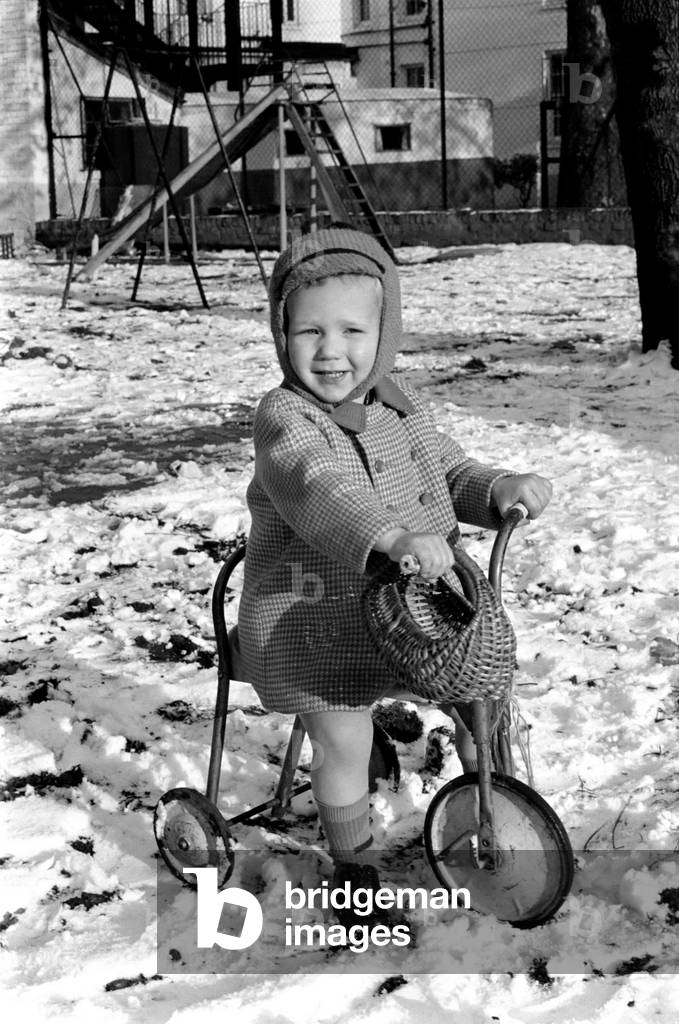 Young boy Robert playing on his bicycle in the snow. November 1969