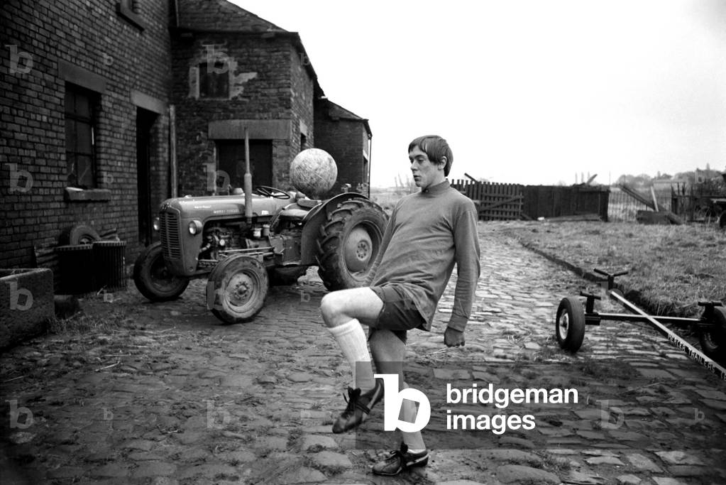 Sport. Football: Sixteen yr old Ronald Aspinwall. He manages Carr Farm. Lathom, near Ormskirk and has been approached by a Chelsea FC coach. Training during his lunch break in the farmyard Ronald Aspinwall practises ball control. December 1969 (photo)