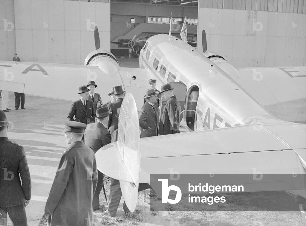 British Prime Minister Neville Chamberlain talks with Lord Halifax (in bowler hat) at Heston airport before leaving for a meeting with German Chancellor Adolf Hitler in Munich, 15th September 1938 (b/w photo)