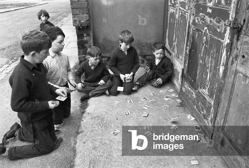 Memories of pre-war cigarette cards are stirred by this scene of young boys playing with large cards which they call 