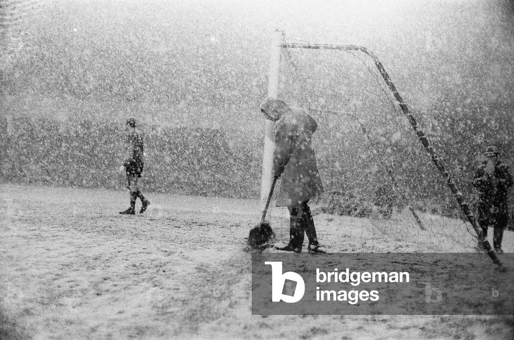 English League Division One match at Highbury, abandoned due to heavy snow. Arsenal v Sheffield Wednesday. A groundsman sweeping the snow away as Peter Springett the Wednesday goalkeeper, walks around his penalty area. 9th December 1967 (photo)