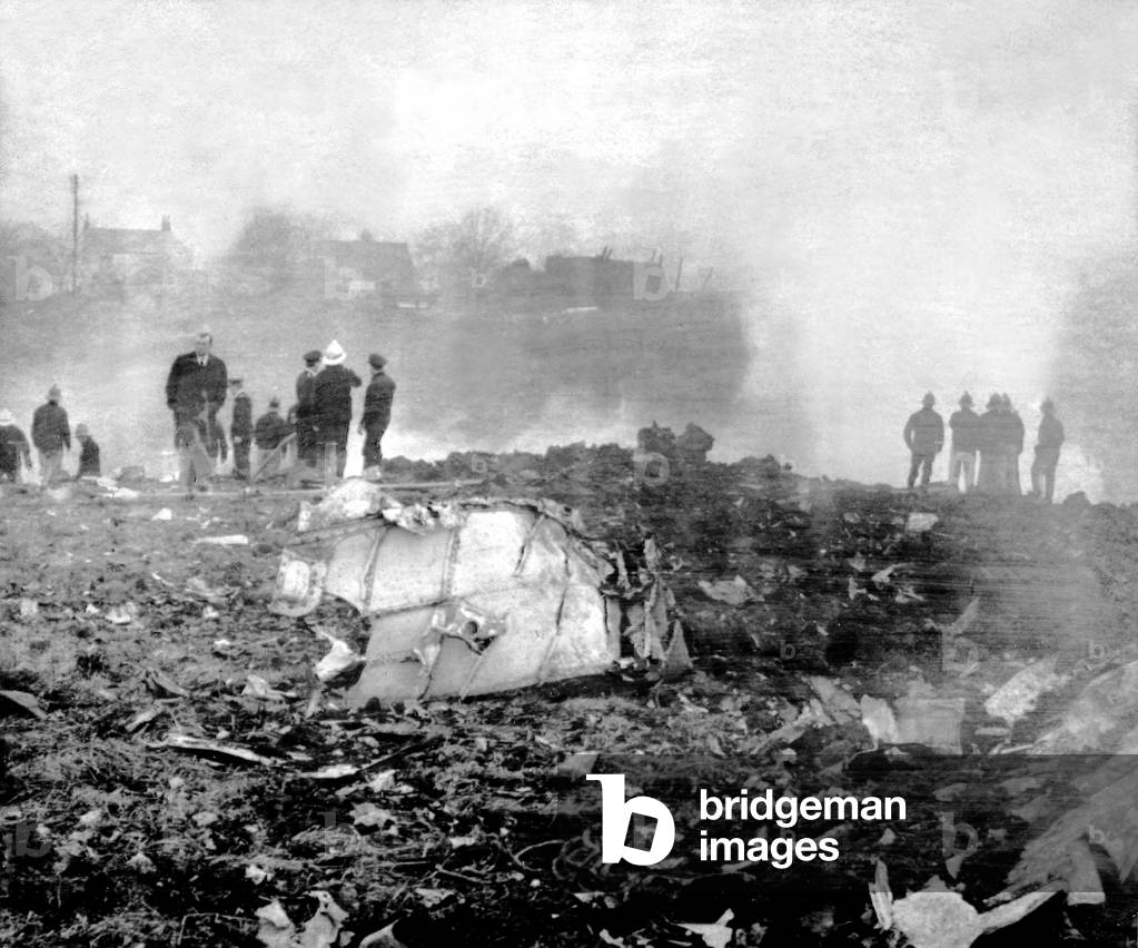 A RAF Vulcan bomber crashed at Wingate, County Durham, after a dramatic life-or-death dash across Northumberland as its crew members baled out one by one, The pilotless aircraft crashed into a field behind the local Co-op shop, several buildings were hit by pieces of metal but no one was reported hurt. Firemen stand by the blazing wreckage. 08/01/1971 (b/w photo)