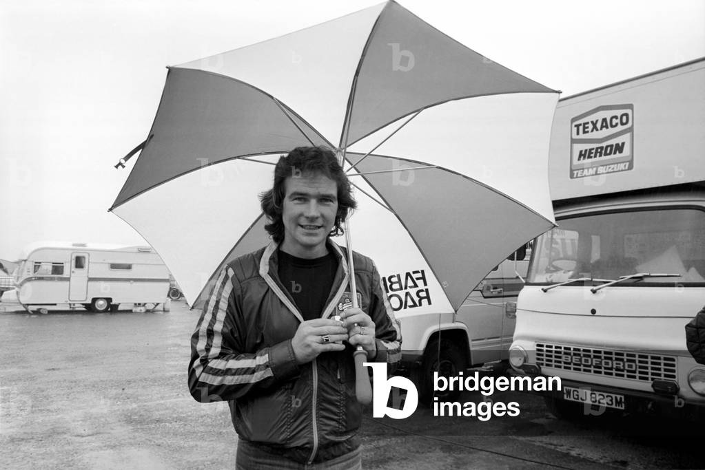 John Player British Grand Prix, Silverstone. Sheene with umbrella in the rain, August 1977 (b/w photo)