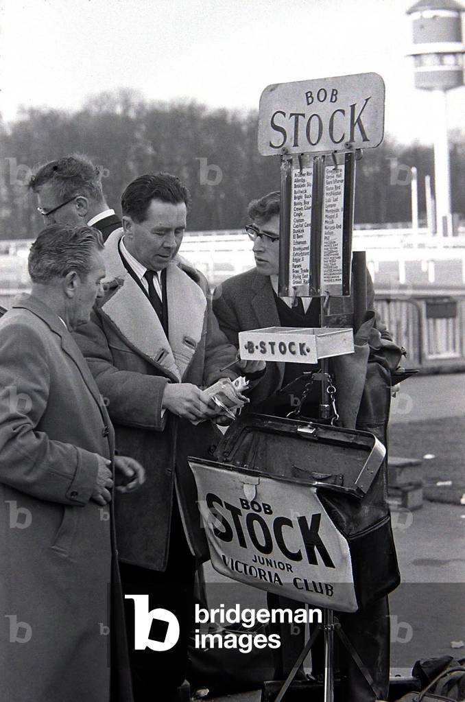 Bookmakers checks his takings after bets were placed for the race, March 1963 (b/w photo)