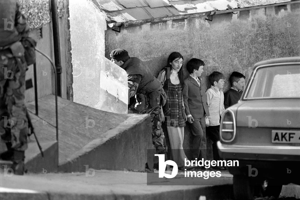 Children seek safety behind Marines shield during riots at Waterside, Londonderry in Northern Ireland. April 1972