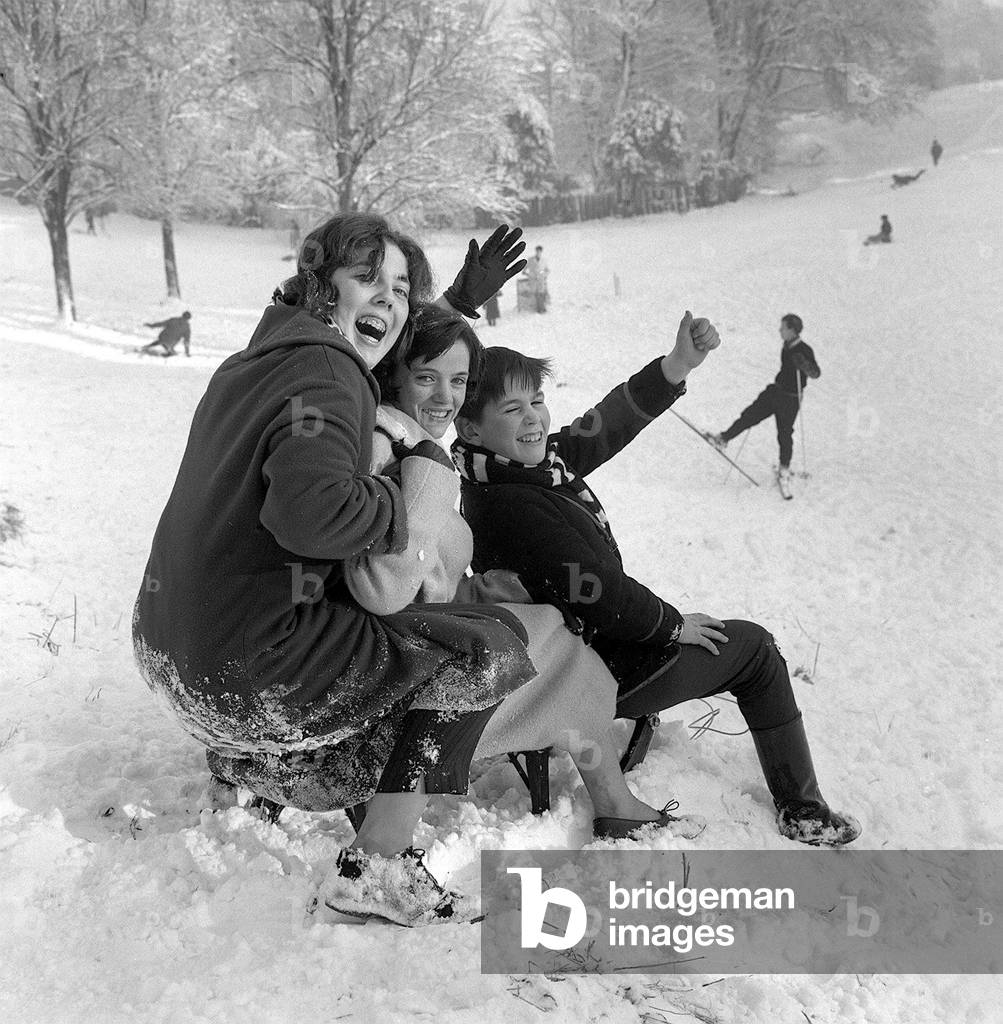 Tobogganists wave to the Mirror photographer before descending Hampstead Heath aboard their sledge on New Years Day 1962