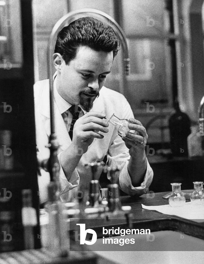 A police forensic laboratory - chemist Neville Dunnett examining a piece of evidence in the lab, c.1960