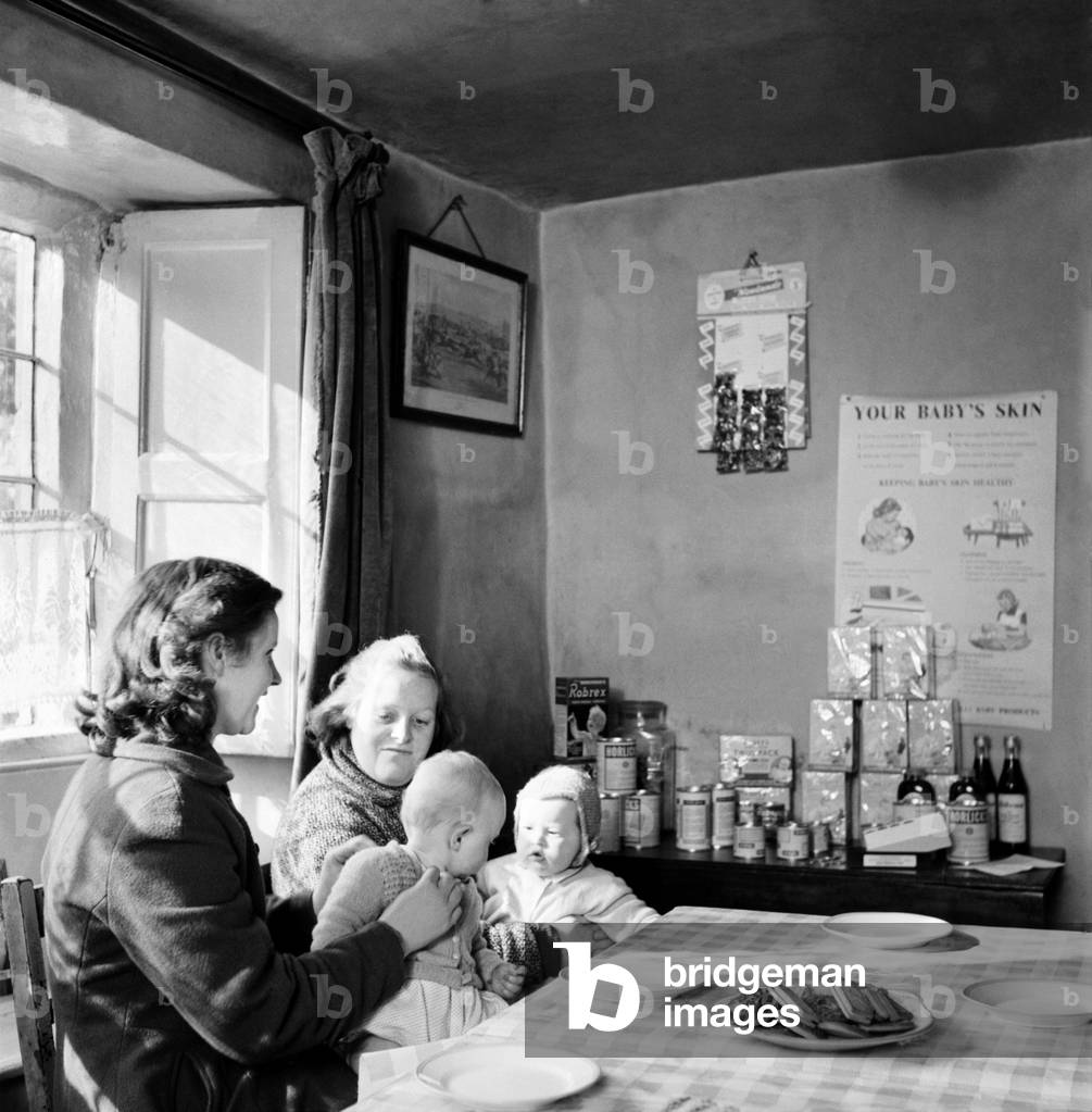 Medical Baby Clinic: Once every week the Falklands Arm pub near Stratford stops serving beer and becomes a baby clinic. Where mums can bring their babies to be clock by the doctor and to hare a cup of tea and a gossip, March 1958 (b/w photo)