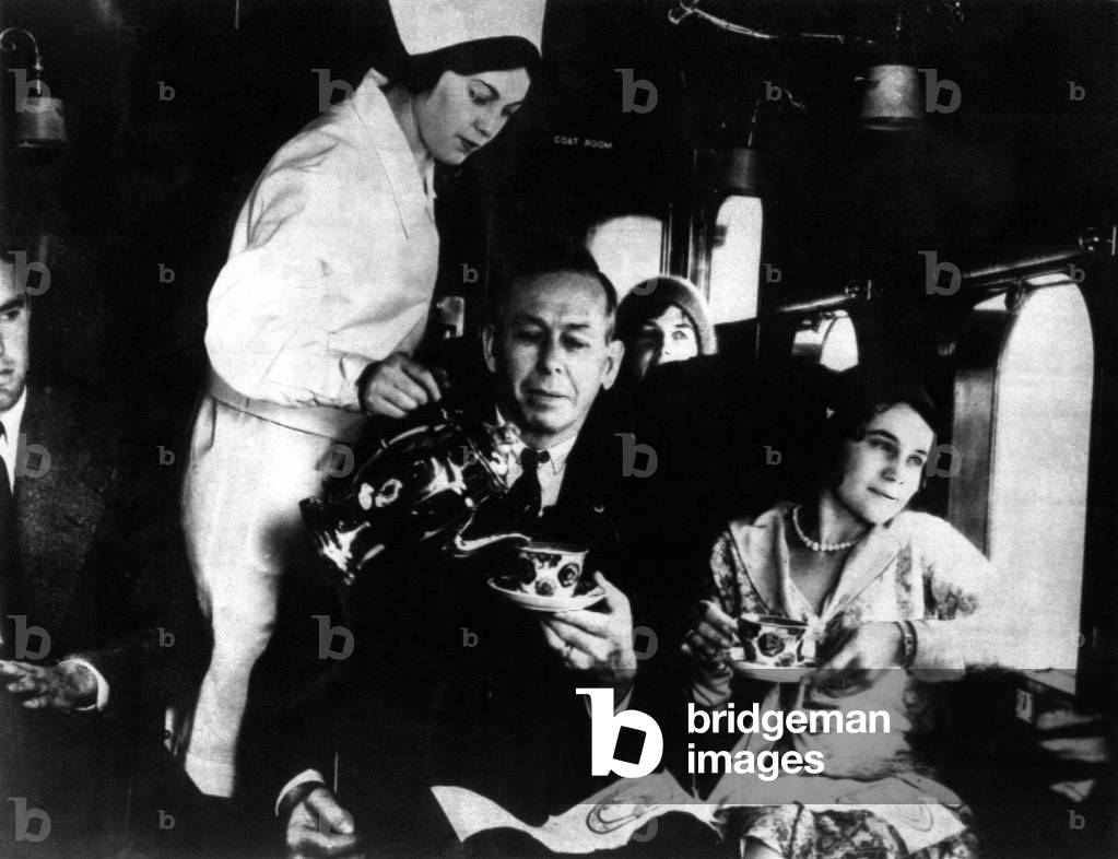 This is what 'in flight service' looked like at the time of the early airlines. That's a hostess not a nurse doing the pouring with the chic coffee pot. Circa : 1930 (b/w photo)