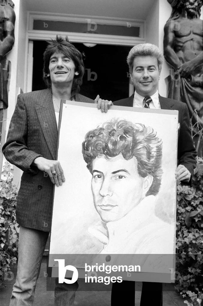 Rolling Stones: Ronnie Wood holds a painting of author Ken Follett who stands next to him. September 1987