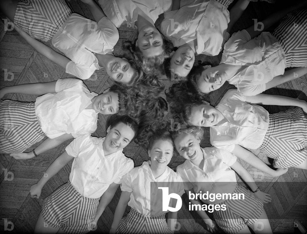 Girls of Aida Foster stage school in North London, lie down next to each other forming a circle on the floor, 18th November 1952 (b/w photo)