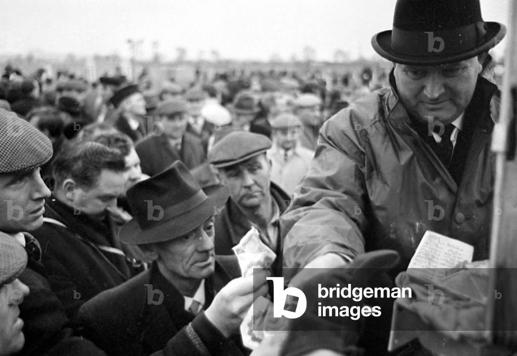 Bookmaker taking bets from crowds of punters before the race at Leopardstown in Ireland
March 1967