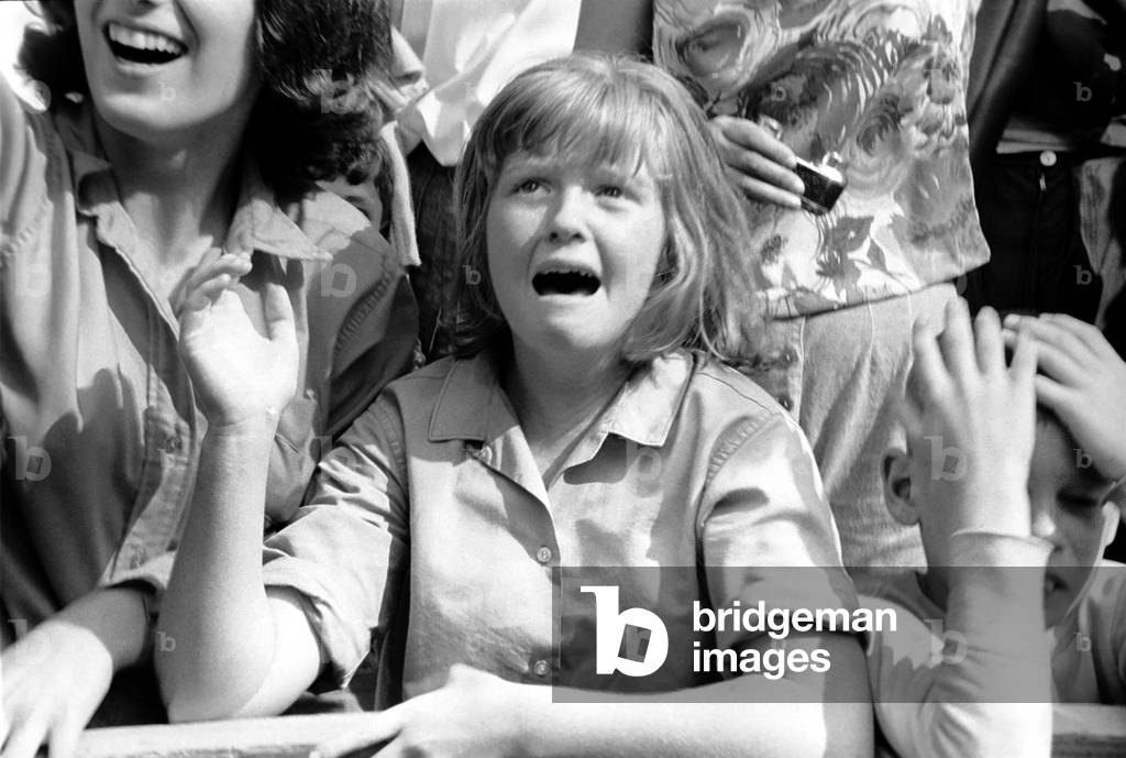 Screaming Beatles fans cheer for their idols on the streets of New York City, USA as the British pop group arrive for their American tour. 
August 1964