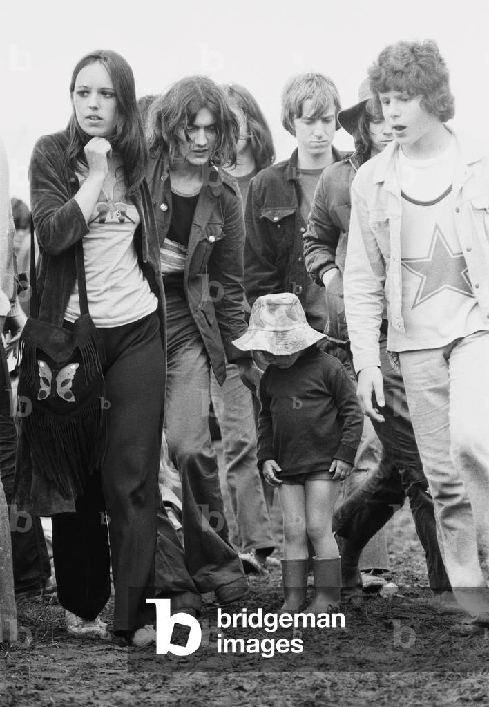 Reading Pop Festival. Young festival goers with small child wearing her wellington boots as she plays in the mud at the festival, 26th June 1971 (b/w photo)