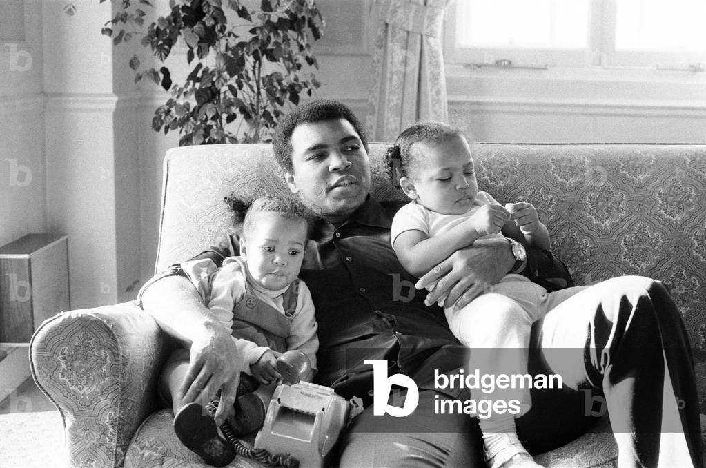 Muhammad Ali cuddling his daughters Laila, (left )and Hana (right) at a Hotel in London England. 19th December 1978 (b/w photo)