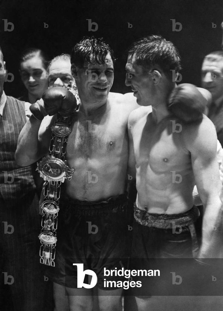 Vince Hawkins, the winner, holding the Lonsdale belt, with Ernie Roderick looking on following their Welter Weight title fight at the Royal Albert Hall . October 1946