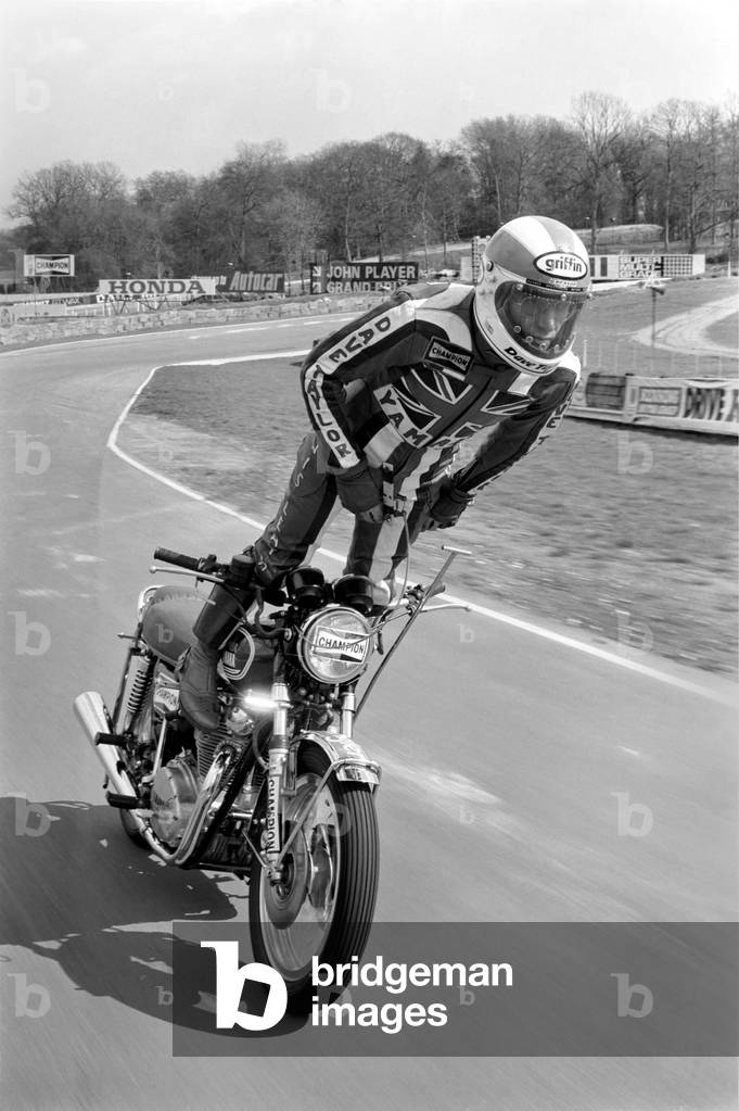 Motorbike stunt: Dave Taylor performing a tank stand at 90 M.P.H, April 1977 (b/w photo)
