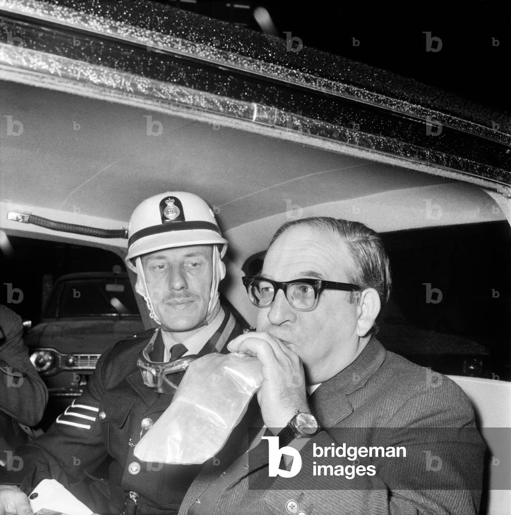 Politics. Transport. Road safety: The Minister of Transport, Mr. Fred Mulley was 'breathalysed' this morning from Police Sergeant Syd Furner, and then had a blood sample taken by experimental Lab Technician Gillian Martin as a demonstration for the Press. The Minister blowing into the bag, in the back of his car for Sergeant Syd Furner. November 1969