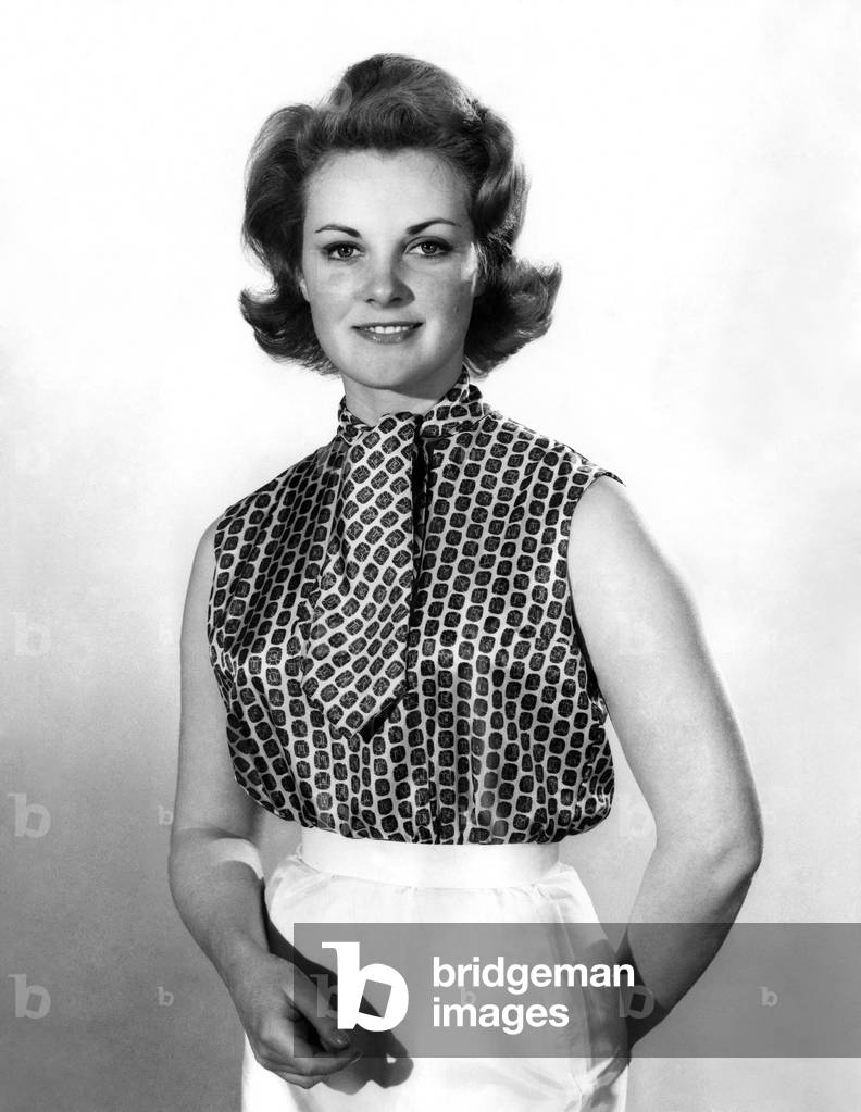 Model Roma Reeves wearing a sleeveless paterned shirt and matching tie.
April 1962
