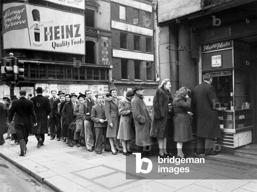 The Cigarette Queue - The cigarette supply has arrived at this Oxford Street kiosk. As many women as men go to make it up.