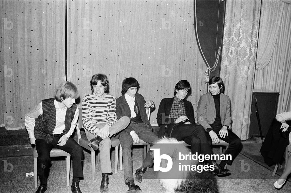 The Rolling Stones at a press conference after meeting fans on Broadway with an Old English Sheepdog in the foreground. l-r Brian Jones, Mick Jagger, Bill Wyman, Keith Richards and Charlie Watts. 2nd June 1964 (b/w photo)