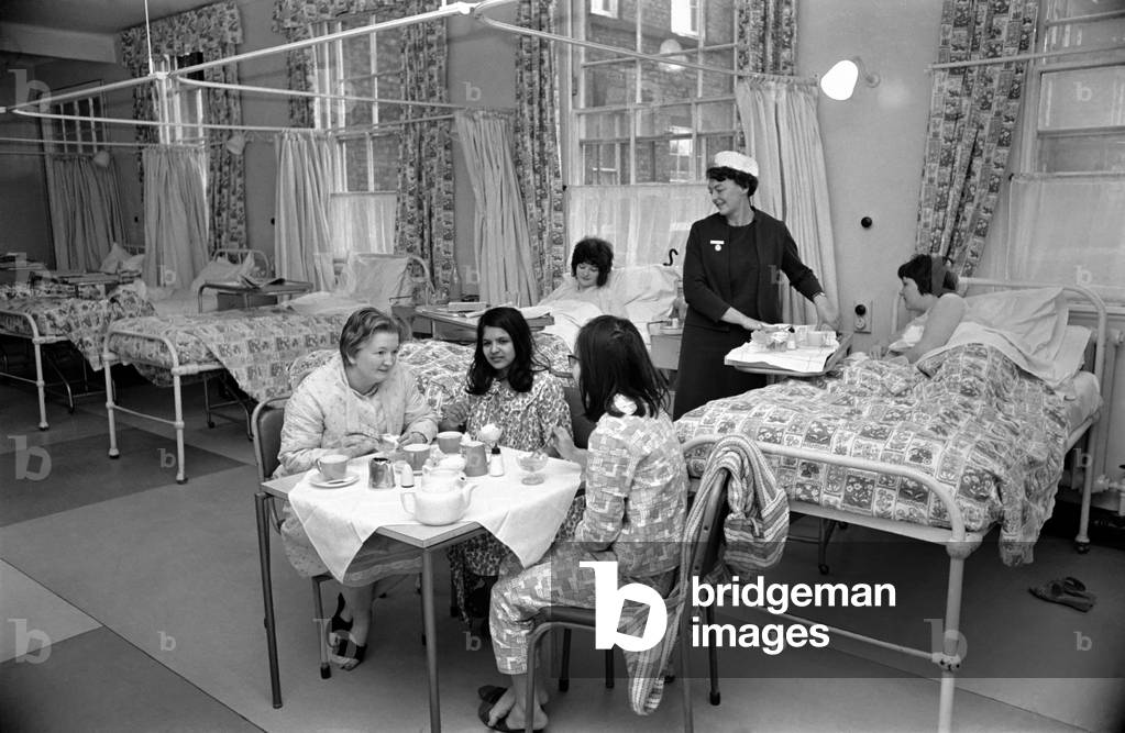 The Good Samaritans stand on parade in a hospital ward. They are some of the volunteers who stopped a small hospital from shutting down. They came to the rescue of matron Miss Queenie Graham after only two nurses turned up for duty. Most of her staff of 31 were victims of the flu epidemic which has hit Merseyside. But willing hands were ready when the call went out for helpers. Nearly 50 offers flooded the switchboard at the 50 bed Sir Alfred Jones Memorial Hospital, at Garston, Liverpool. December 1969