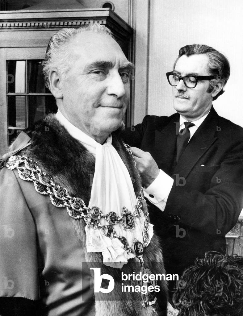 Councillor James Eames being robed by his attendant Mr. Tom Freer before being elected Lord Mayor of Birmingham. Eames is a 57-year-old engine driver. 21st May 1974 (b/w photo)