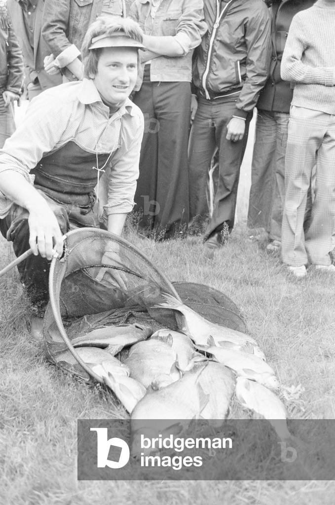 One of the competitors in the Ladbrokes Super League Fishing Competition seen here posing with his catch before the weigh in at Coombe Abbey Lake near Coventry, 24th July 1977 (b/w photo)
