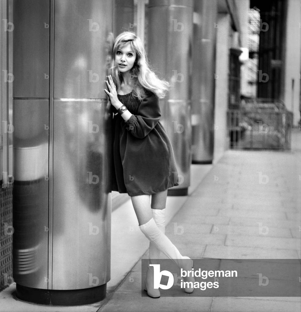 Actress and model Maddy Smith aged 20 photographed in London wearing a black dress and fwhite knee high boots
November 1969