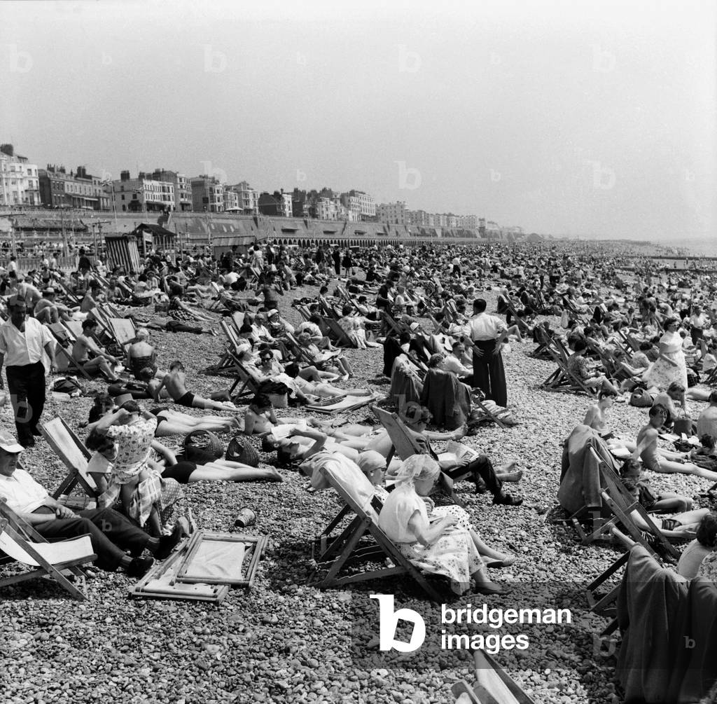 Crowded scenes on Brighton Beach as holidaymakers enjoy the hot summer weather, East Sussex. June 1960 (b/w photo)