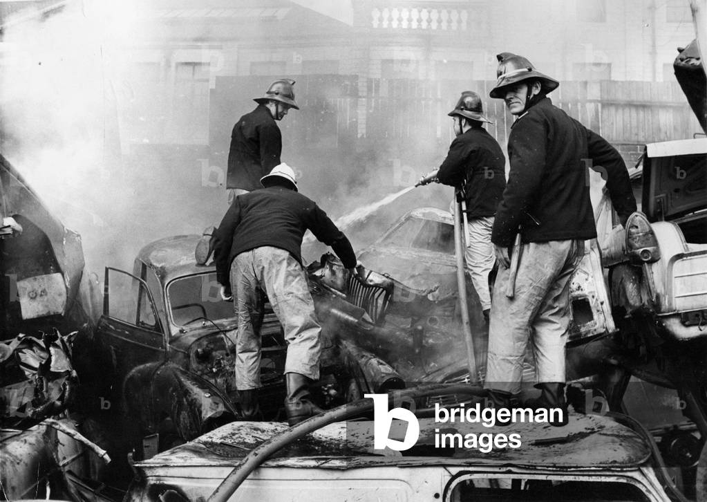 Firefighters scrambled about on piles of old cards to tackle a fire at Benfield Vehicle Dismantlers scrapyard in Newcastle, 1970