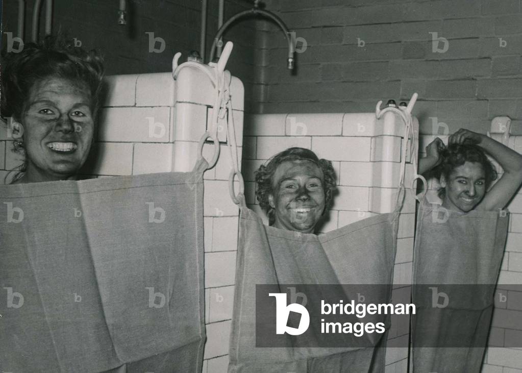 Women Coal screeners with soot covering their faces at Lyme Pit in Lancashire coming off shift wash in the pithead showers November 1948 (b/w photo)