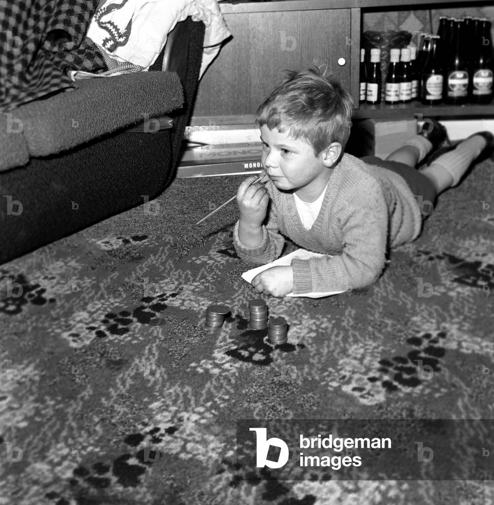 Police with children: Simon Dingley aged 4 of Arthur Street Little Lever was terribly upset when he saw on television that Father Xmas had been arrested so he sat down and wrote an appeal to the poilce for his release. His sorrow turned to joy today when he was visited by P.C. George Fobersby from the Bolton Police force who put him in touch with the station by phone to receive an assurance that the distinguished visitor would be around as usual. Simon is seen here counting out his saved pocket money just in case Santa needs to be bailed. December 1969