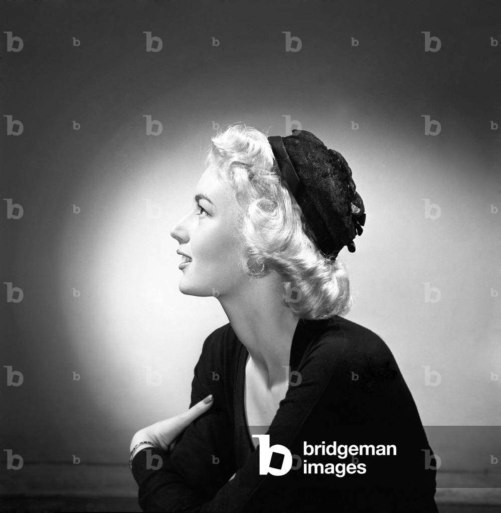 Woman modelling the latest 1956 hat fashions in the Reveille studios, June 1956 (b/w photo)