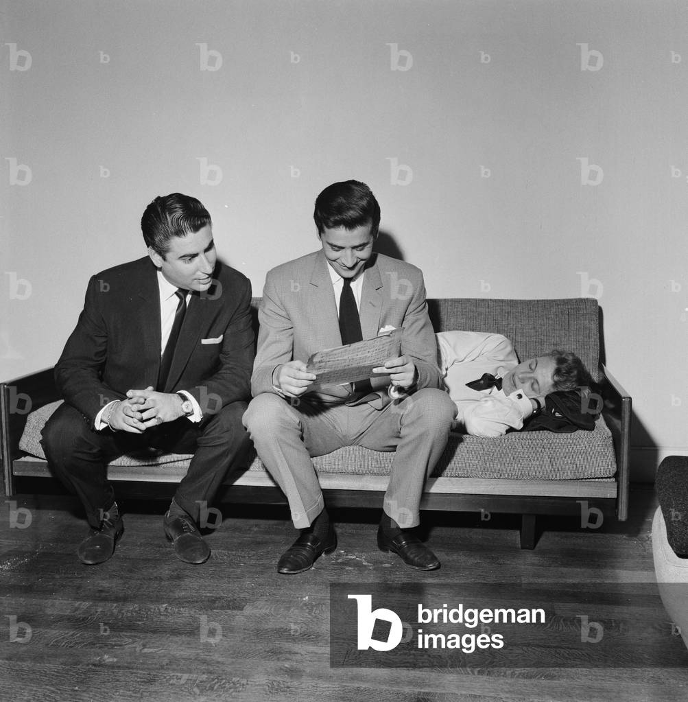 Larry Parnes (left) and John Kennedy (centre), Managers of singer Tommy Steele, who is pictured sleeping on sofa, 28th April 1961 (b/w photo)