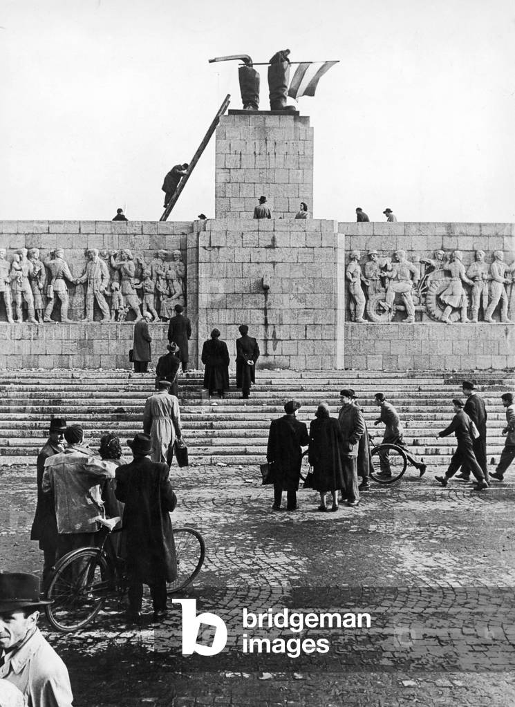 Freedom fighters flying the flag from the boots of what was left of the statue of Stalin during the Hungarian Revolution, 1956 (b/w photo)
