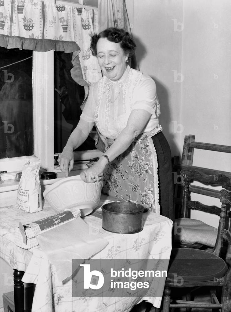Domestic scenes: A woman making cakes in her kitchen at home. 1954.