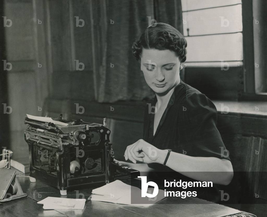 Female office worker checking her watch, June 1937 (b/w photo)
