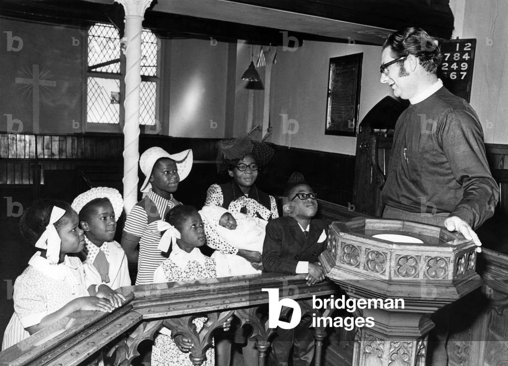 Coal Mining Accident: The minister of the Roscoe Place Methodist Church Leeds explains the procedure of todays (sunday) christening of baby Sydney Brown to Mrs. Brown and her family. He is Rev. Trevor Bates. June 1973 P017847