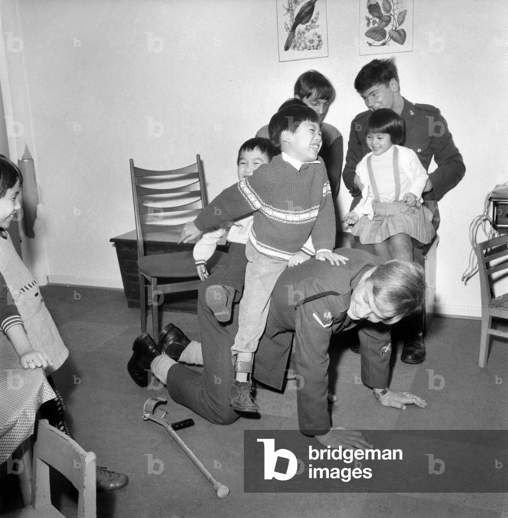 Vietnamese children playing with a British soldier in Peaceville, West Germany. It's a haven for child victims of the Vietnam war.