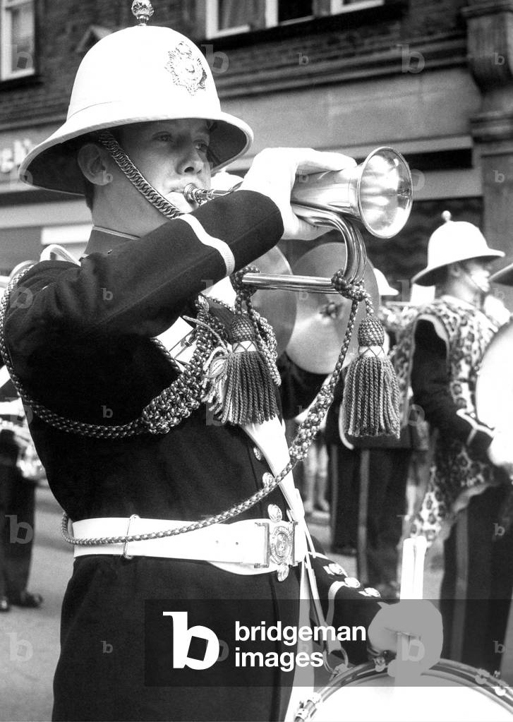 A bandsman playing the bugle and snare drum in July 1977 (b/w photo)