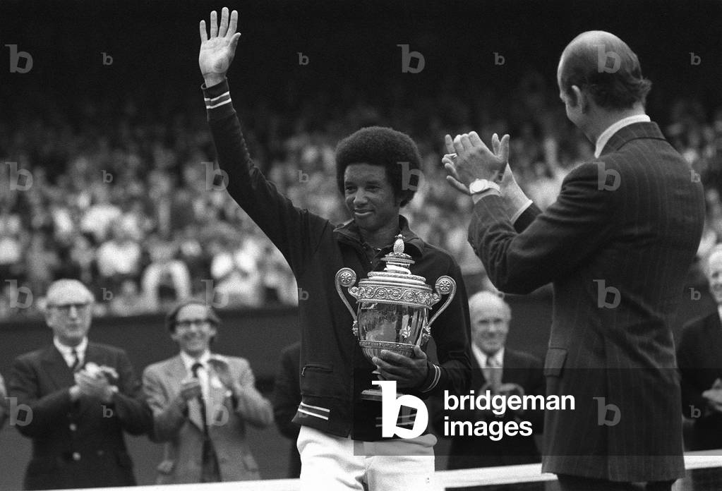 Arthur Ashe waves to fans after winning mens title in 1975 at Wimbledon with Duke of Kent applauding