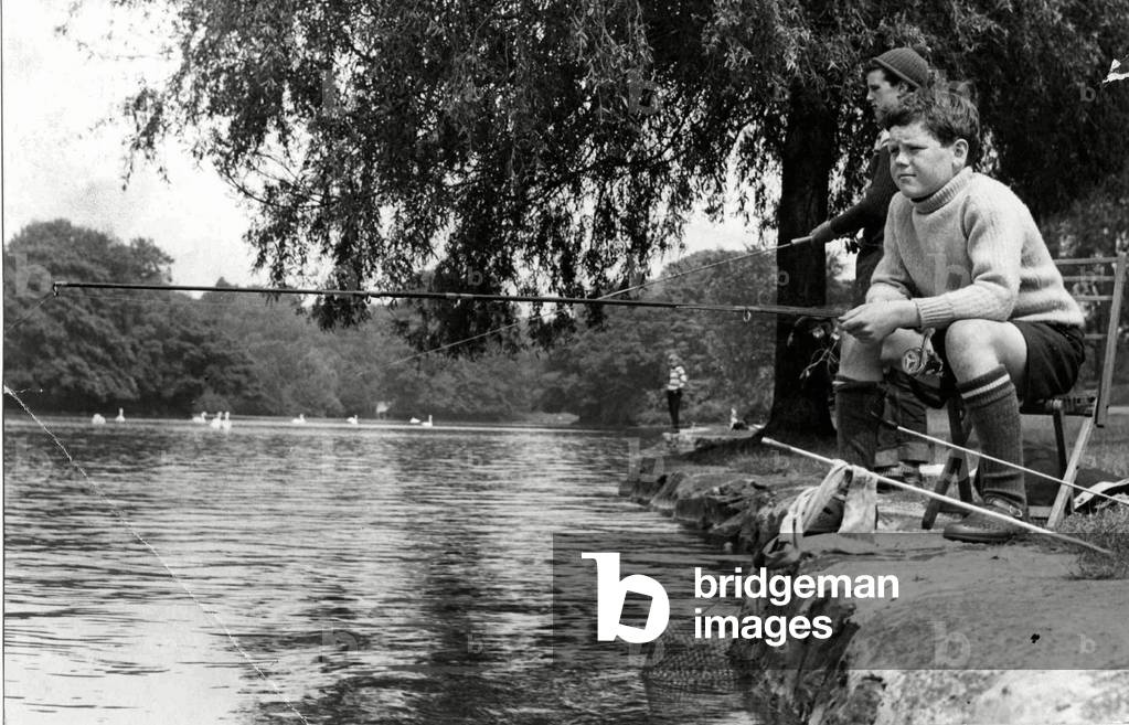 Concentration and determination reflected on the faces of these young fishermen enjoying the sunshine during the school summer break at Roath Park Lake, Cardiff. 10th August 1965 (b/w photo)