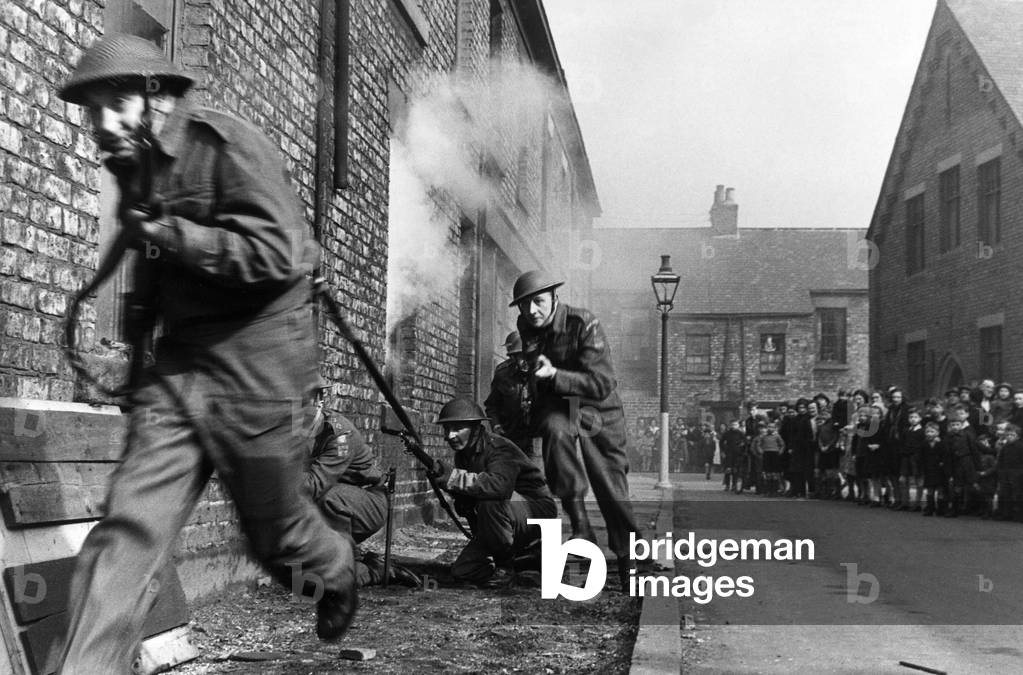 Members of the Home Guard running through a training exercise in a residential street in Newcastle as residents gathered at the bottom of the road look on.
6th April 1942